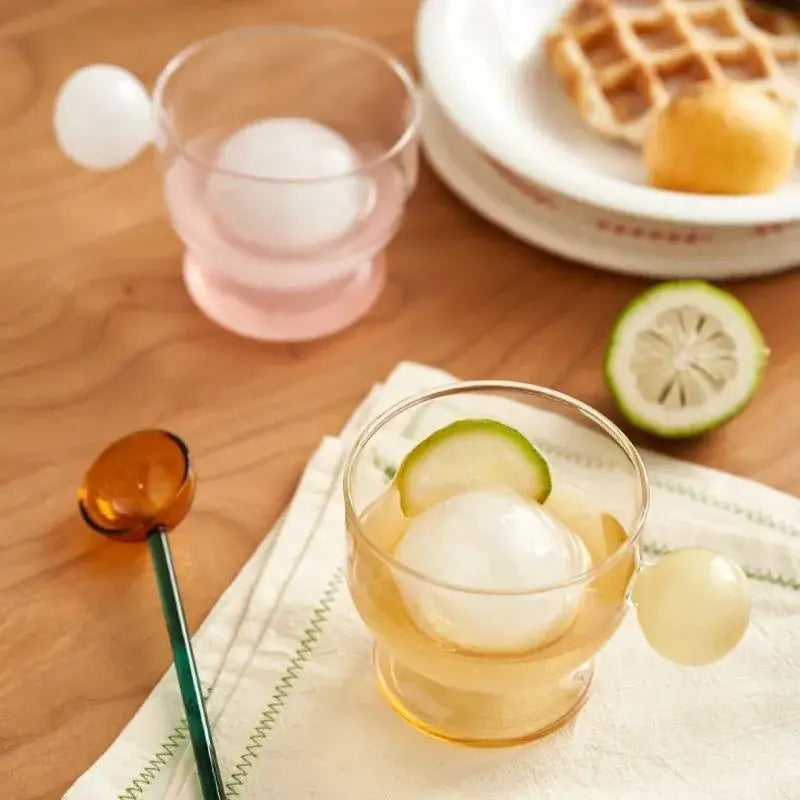 Modern glass coffee mug with transparent body white spherical handle and lemon slice decor