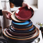 A stack of modern glazed decorbites ceramic round plates in deep colors with earthy brown rims for dining use