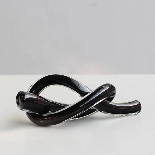 A sleek glossy black geometric glass sculpture with a smooth intertwined knot design for modern decorbites decor