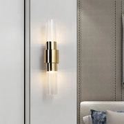 Modern gold two light sconce with clear ribbed glass cylindrical accents and bulb base for bathroom use