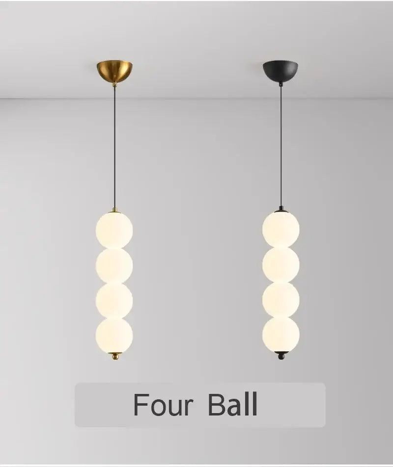Two minimalist pendant lights with four frosted glass spheres and plated gold-toned surface as dining room focal point
