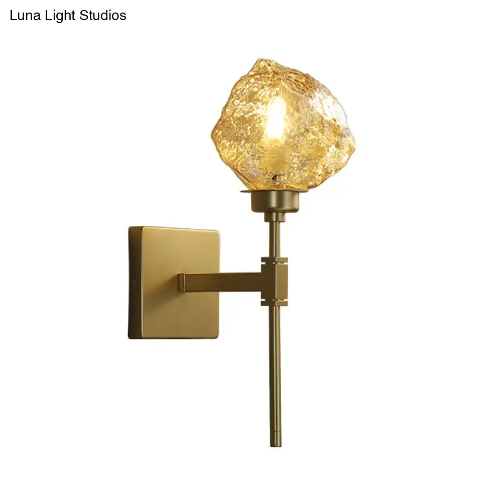 Modern gold wall sconce with textured amber smoke gray glass shade shaped like an irregular rock for living room lighting