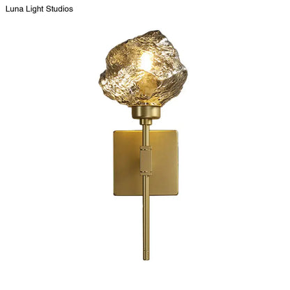 Modern gold wall sconce with amber smoke gray textured glass shade shaped like an irregular rock for living room lighting