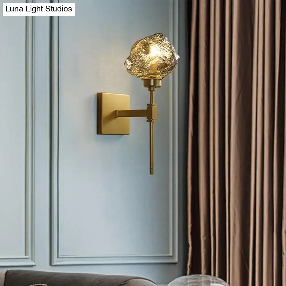 Modern gold wall sconce featuring a textured amber smoke gray glass globe for living room lighting