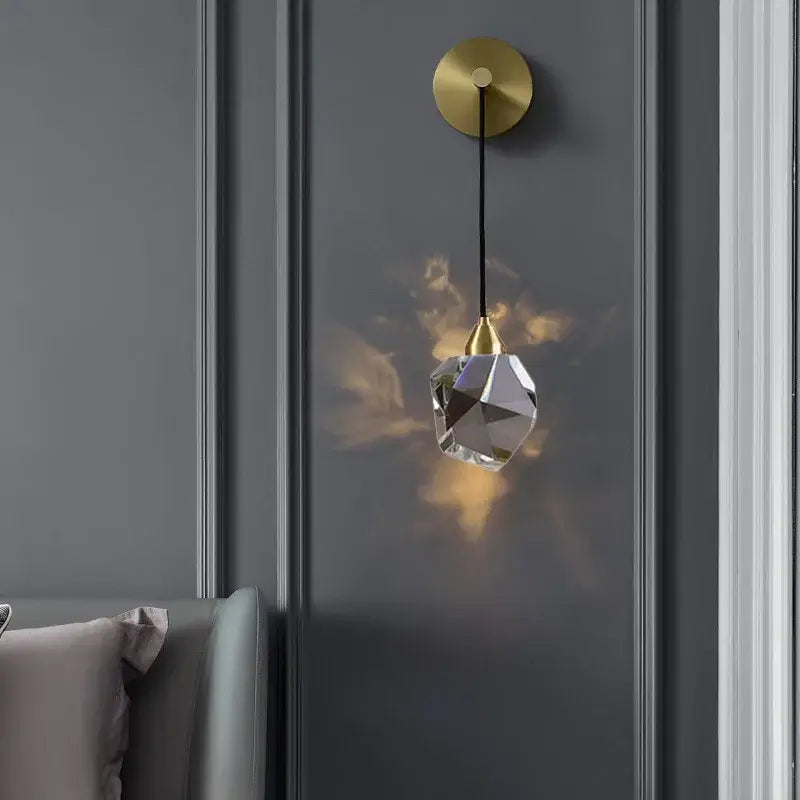 Modern gold and black crystal wall sconce with faceted glass shade refracting warm light decorbites crystal wall