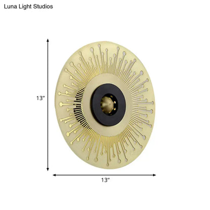 Modern gold and black laser cut disk wall sconce with cream base, gold spikes, and black mounting ring for bedroom lighting