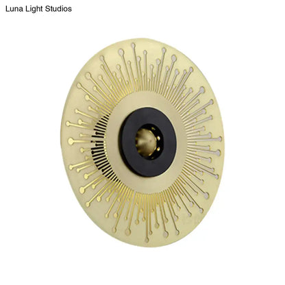 Modern gold and black laser cut disk wall sconce with sunburst design and black central accent for bedroom lighting