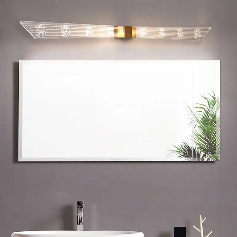 Modern gold and black led vanity sconce light with sleek white framed rectangular bathroom mirror reflecting greenery