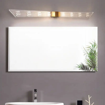 Modern gold and black led vanity sconce light with sleek white framed rectangular bathroom mirror reflecting greenery