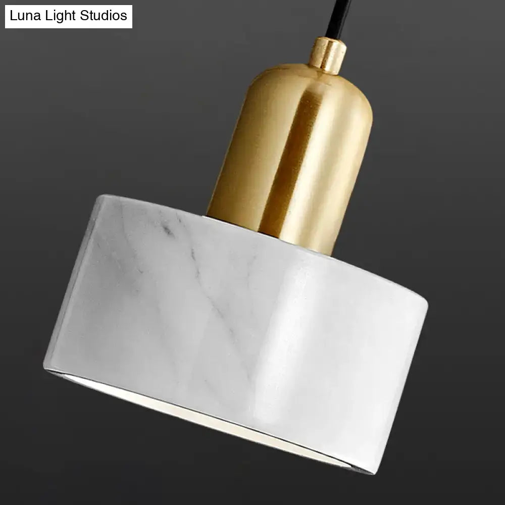 A modern living room pendant light fixture with a white marble shade gray veining and polished gold-toned metal
