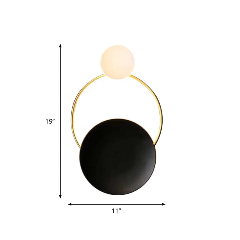 Modern minimalist wall sconce featuring a sleek gold-toned circular frame with two spherical elements , one matte black and one frosted glass orb.