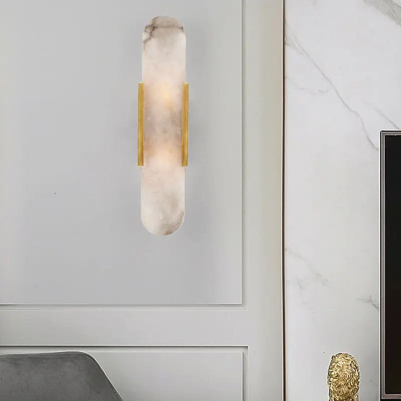 A modern wall lamp featuring a translucent white marble body with polished gold bars for living rooms