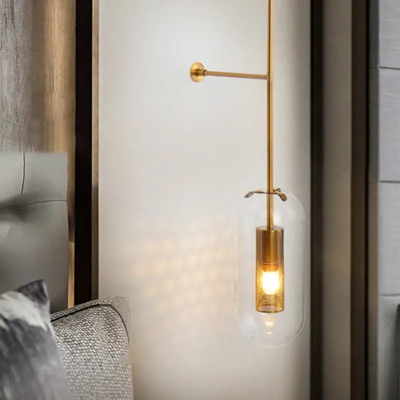 Modern gold and black orb wall lamp with gold-toned sconce, clear glass shade, and mesh cylindrical base for living rooms