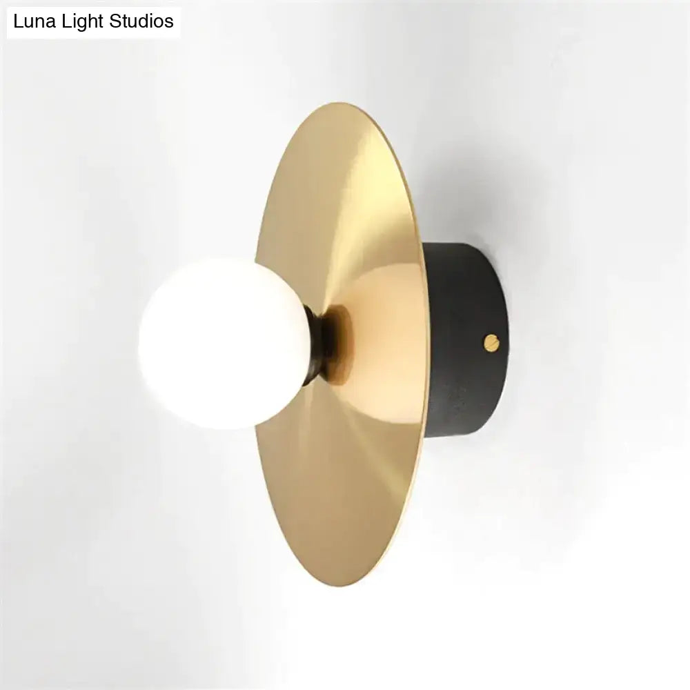 Modern gold and black riya wall light with a gold-toned circular sconce and matte black base for bedroom use