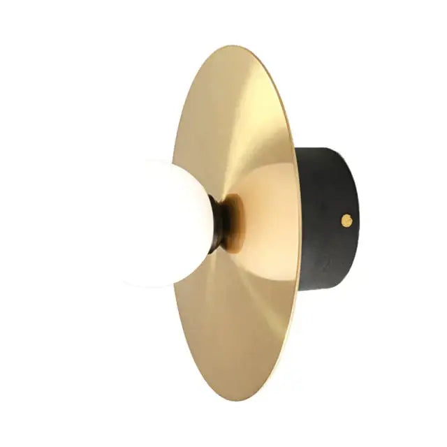 Modern gold and black riya wall light with a gold-toned brass disc and matte black backplate for bedroom use