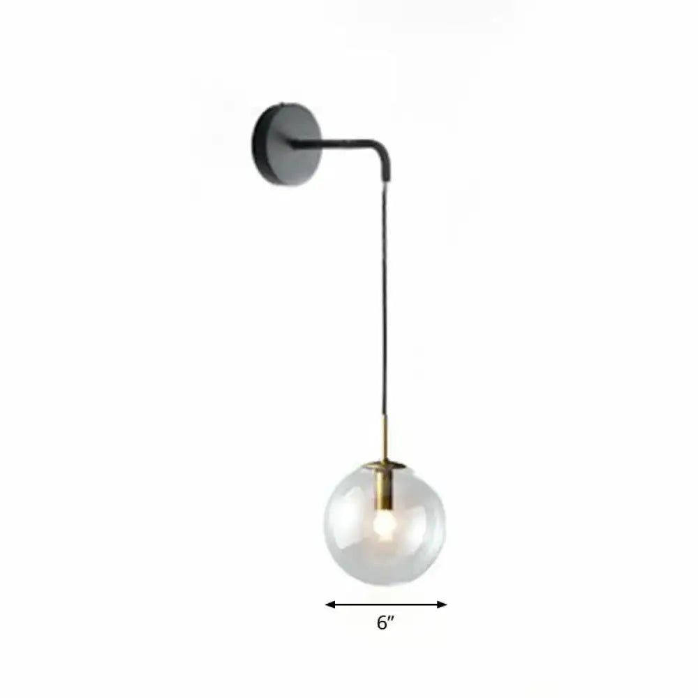 Modern gold and black spherical glass wall light featuring a brass-accented light bulb for living room use