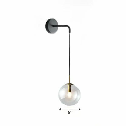 Modern gold and black spherical glass wall light featuring a brass-accented light bulb for living room use