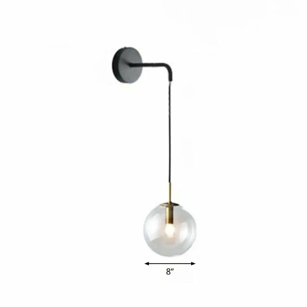 Modern gold and black spherical glass wall light with brass accents and light bulb for living room use