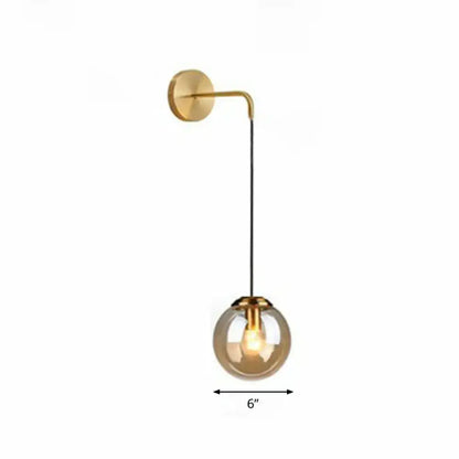 Modern gold and black spherical glass wall light featuring a gold-toned curved arm and exposed light bulb type