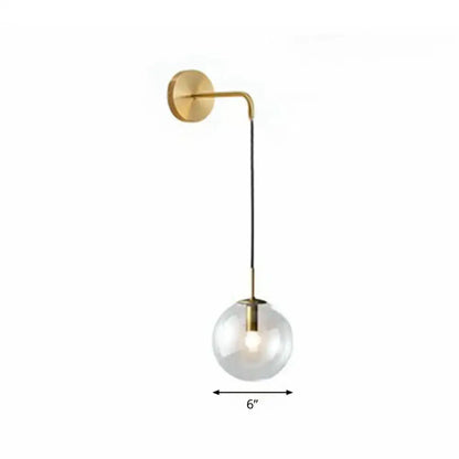 Modern gold and black spherical glass wall light featuring a gold-toned wall sconce with a light bulb and black cord