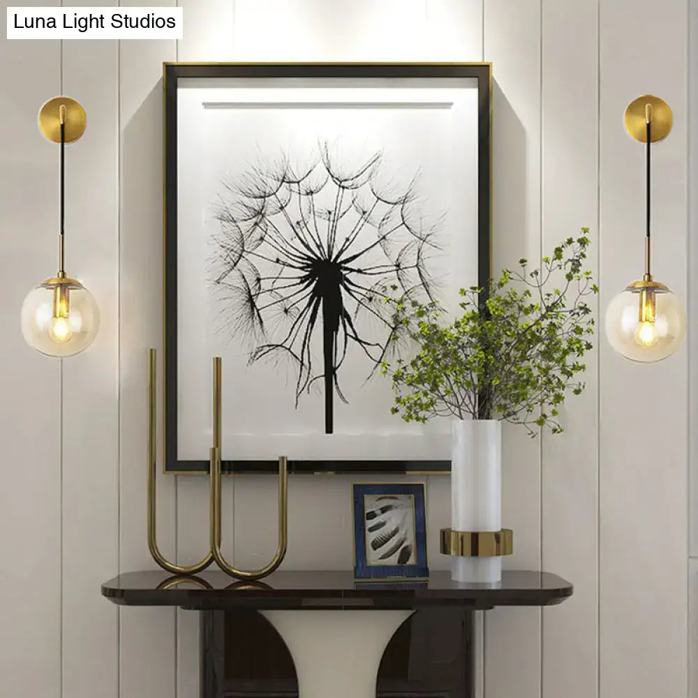 Modern gold and black spherical glass wall light bulbs with gold-finished pendant globes flank black-and-white dandelion art