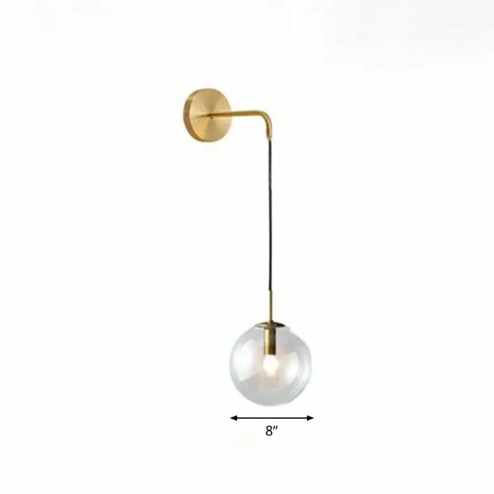 Modern gold and black spherical glass wall light with gold-toned curved arm and clear glass globe shade light bulb