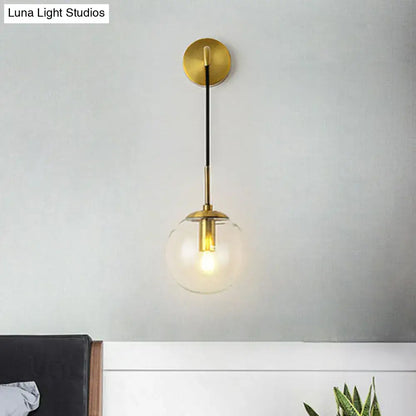 Modern gold and black spherical glass wall light featuring brass-finished sconce with clear globe and black rod for living room light bulb use