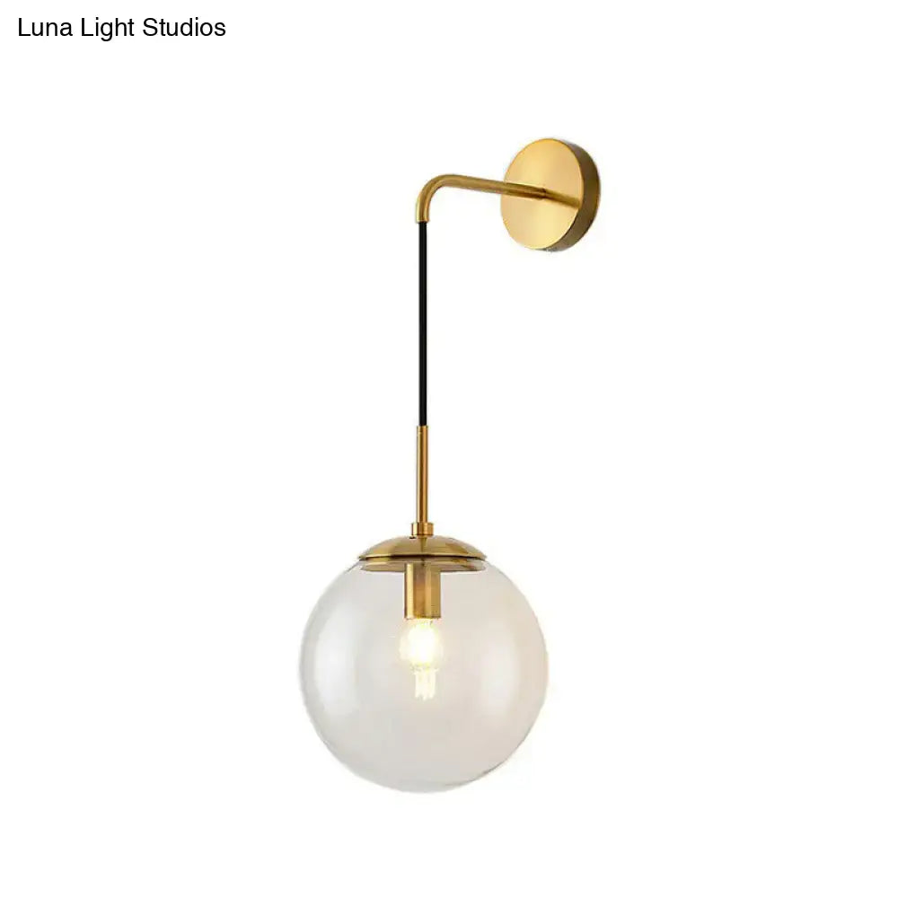 Modern gold and black spherical glass wall light with gold-toned sconce and clear globe featuring a visible light bulb