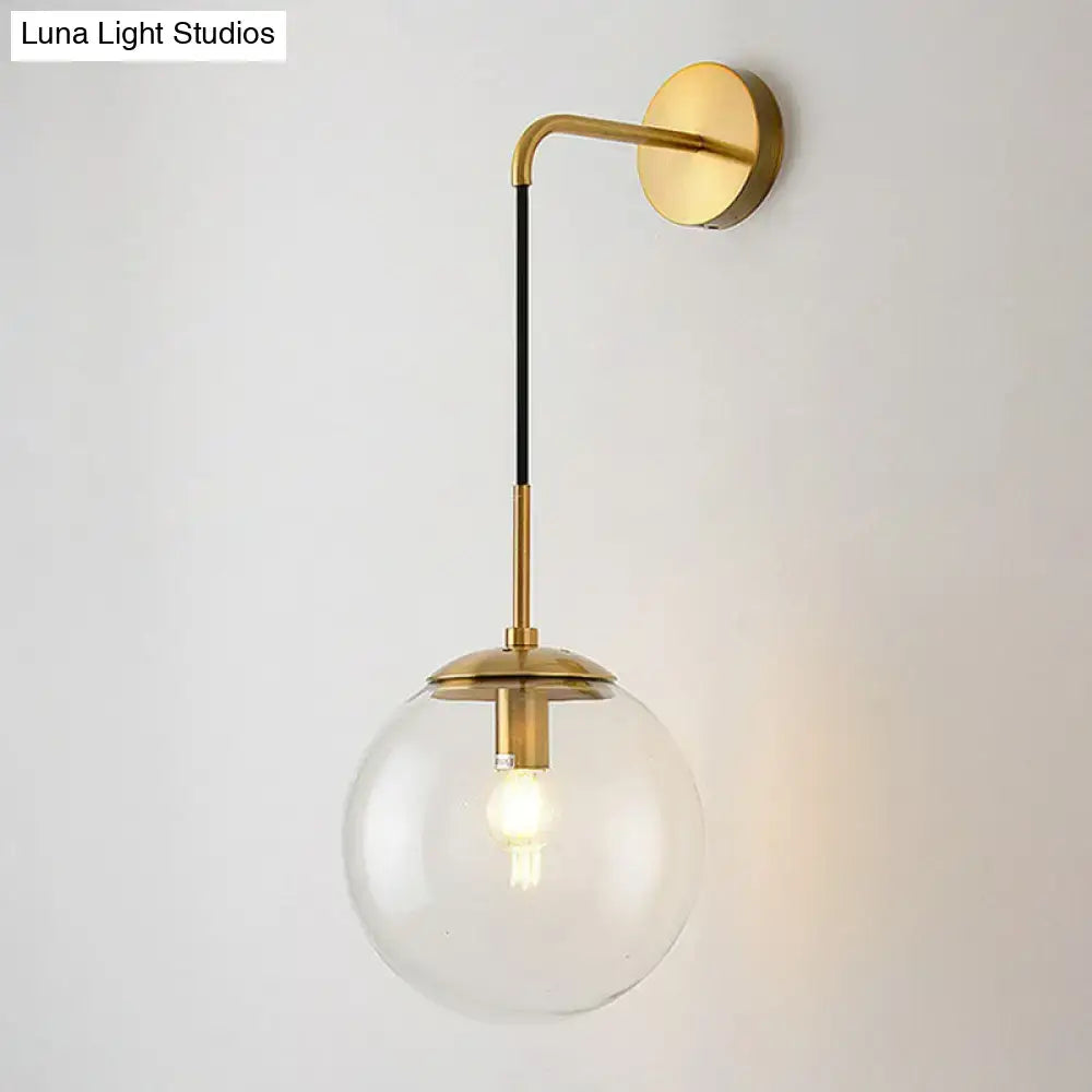 Modern gold and black spherical glass wall light featuring a gold-toned wall sconce and clear glass globe light bulb
