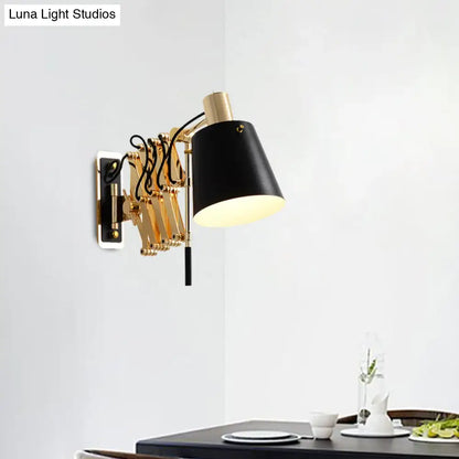 Modern gold and black wall sconce with barrel shade, articulated metal arms, and brass-finished base for bedroom lighting