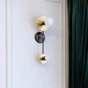 Modern gold and black wall sconce with opal glass shade featuring two frosted globe bulbs and black circular base