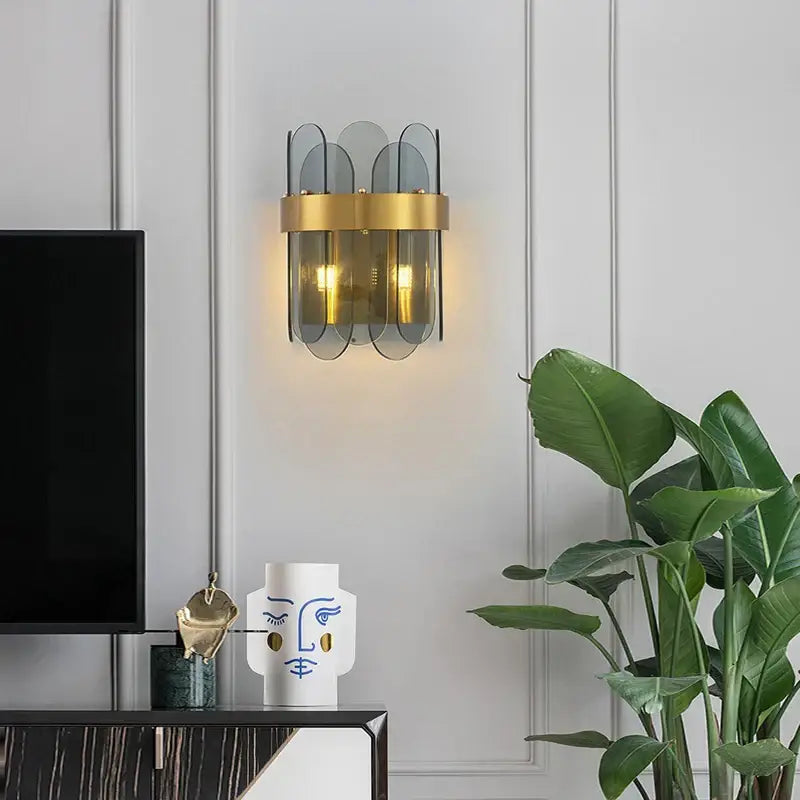 Gold-toned wall sconce with curved glass panels providing a warm glowing light for dining experience lighting solution