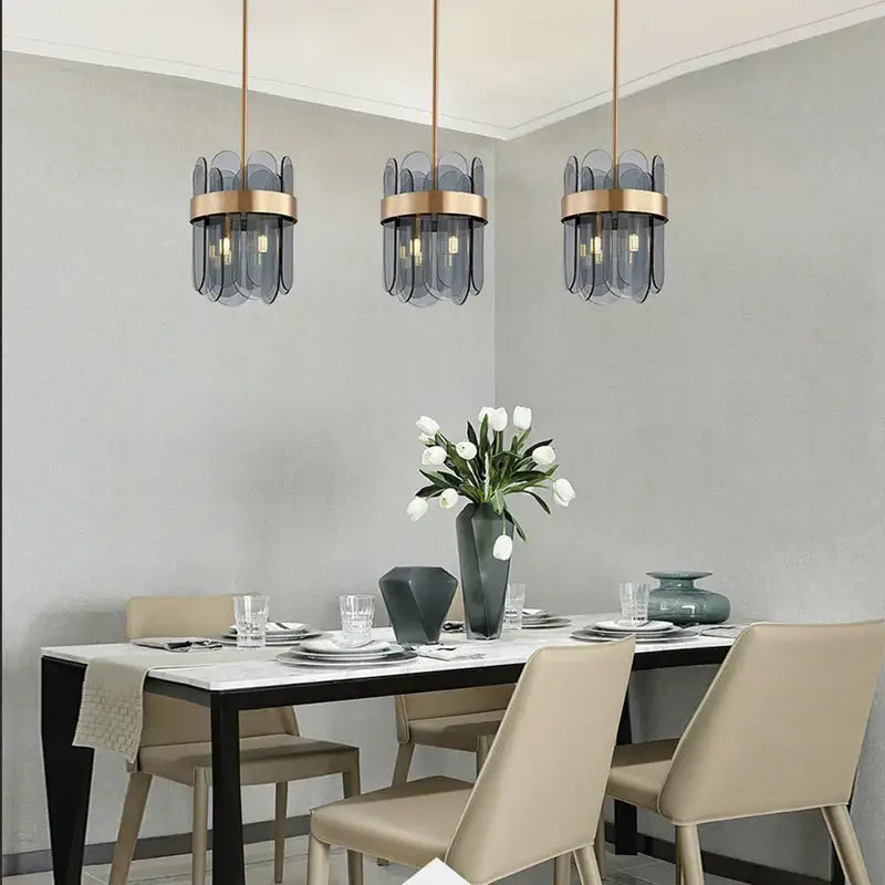 Three modern pendant lights with frosted glass shades and brass accents form a stylish glass chandelier lighting solution