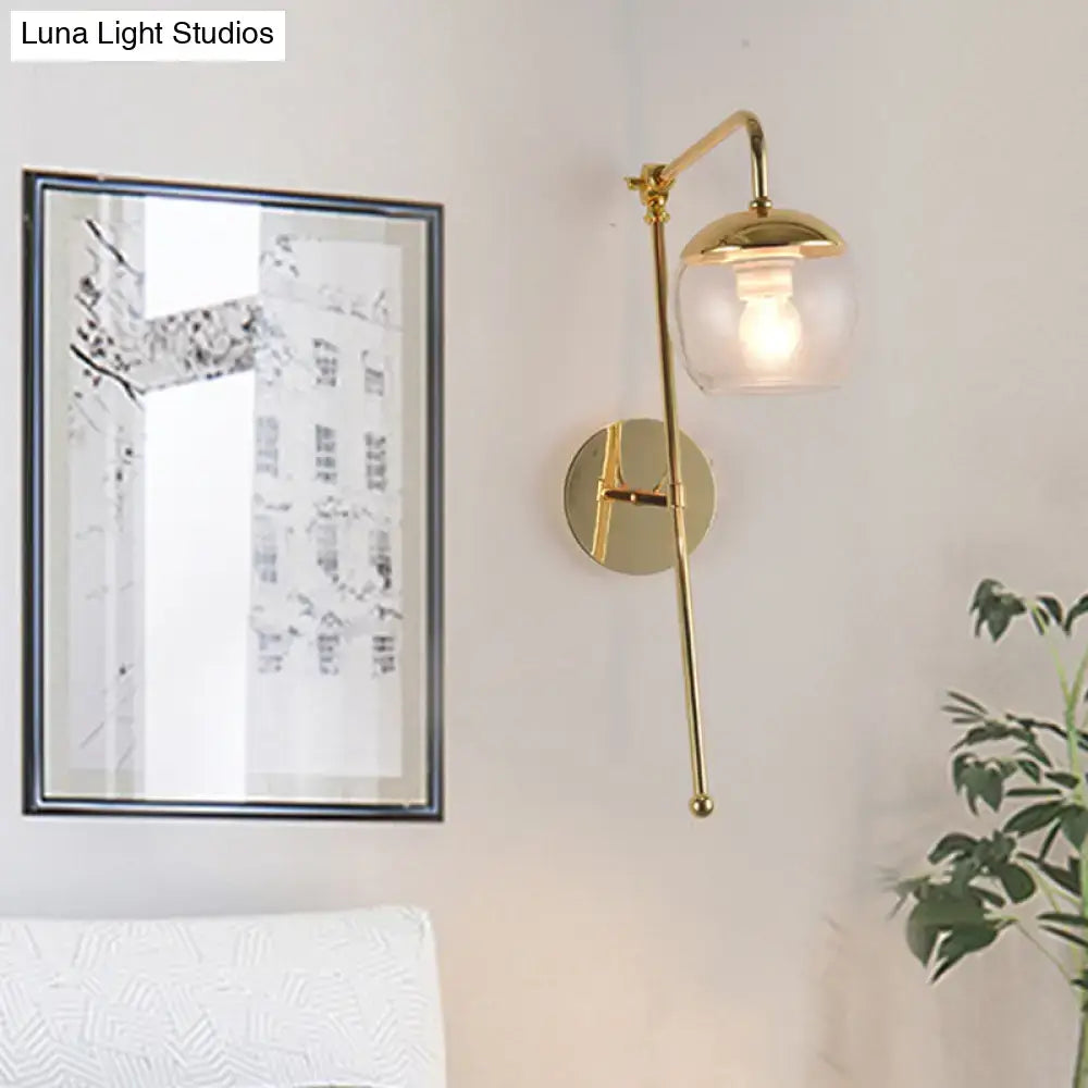 Modern gold wall sconce with clear black glass ball and articulated arm, ideal for bedroom wall lighting