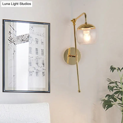 Modern gold wall sconce with clear black glass ball and articulated arm, ideal for bedroom wall lighting