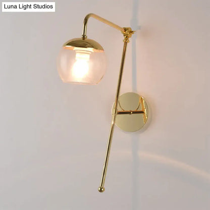 A sleek modern gold wall sconce with clear black glass ball shade for bedroom light fixture design