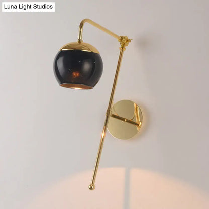 Modern gold and clear black glass ball sconce featuring a gold finish and sleek spherical black glass shade for bedroom walls