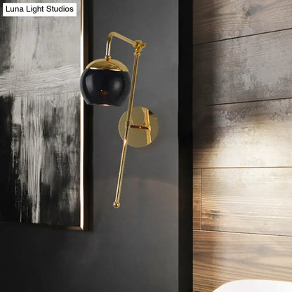 Modern gold and clear black glass ball sconce with a sleek black spherical lamp and gold-toned curved metal arm wall light