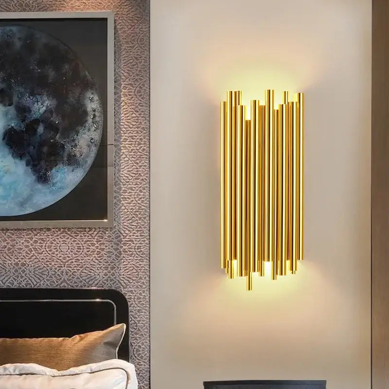 Modern gold and clear glass led wall lamp with vertical cylindrical tubes emitting warm light for bedroom use