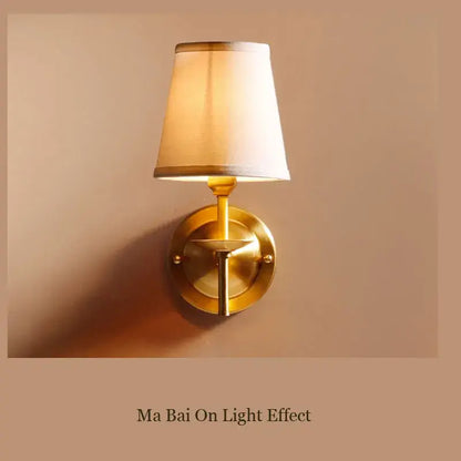 A warm-toned brass wall lamp with a tapered cream fabric shade perfect for modern bedroom decorbites copper wall lamp