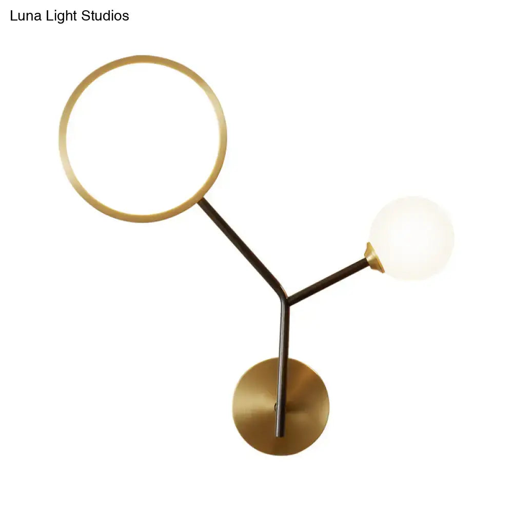 Modern brass-finished wall sconce lamp with circular ring and spherical globe for bedroom lighting use