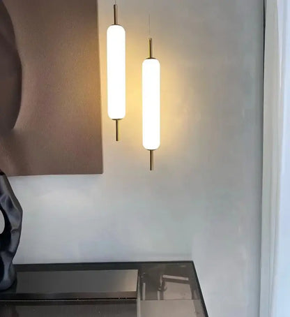 Two sleek gold cylindrical glass led pendant lights with frosted shades hanging side by side for living room