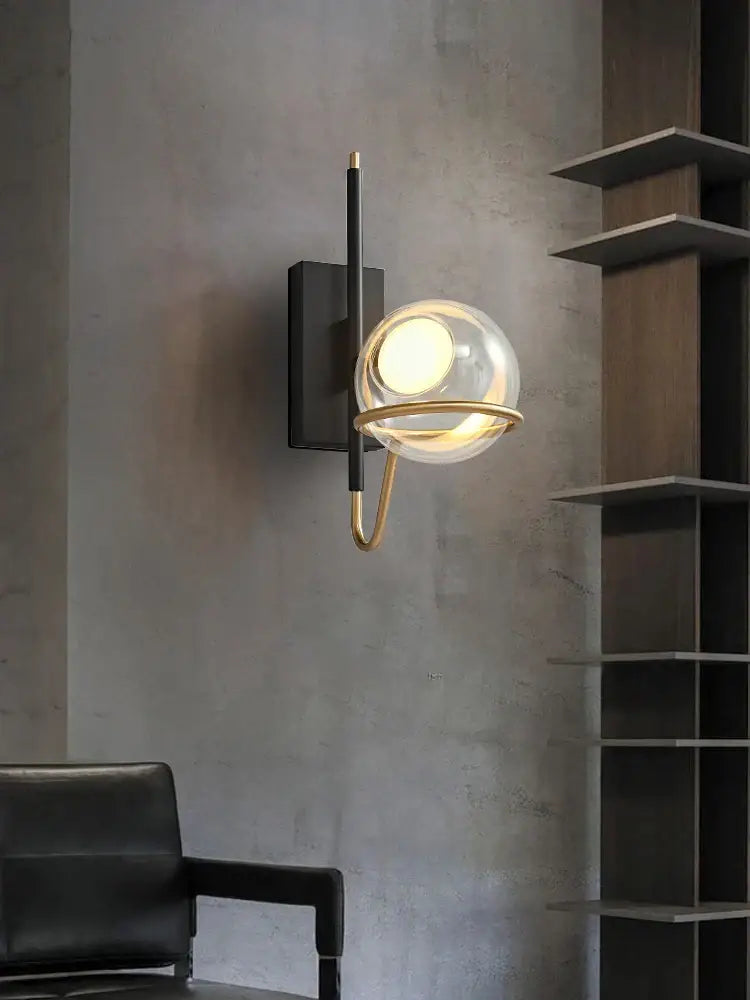 Modern wall sconce with clear gray glass globe, gold metal frame, mounted on black backplate for decorbites gray glass ceiling decor