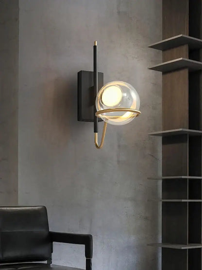 Modern wall sconce with clear gray glass globe, gold metal frame, mounted on black backplate for decorbites gray glass ceiling decor