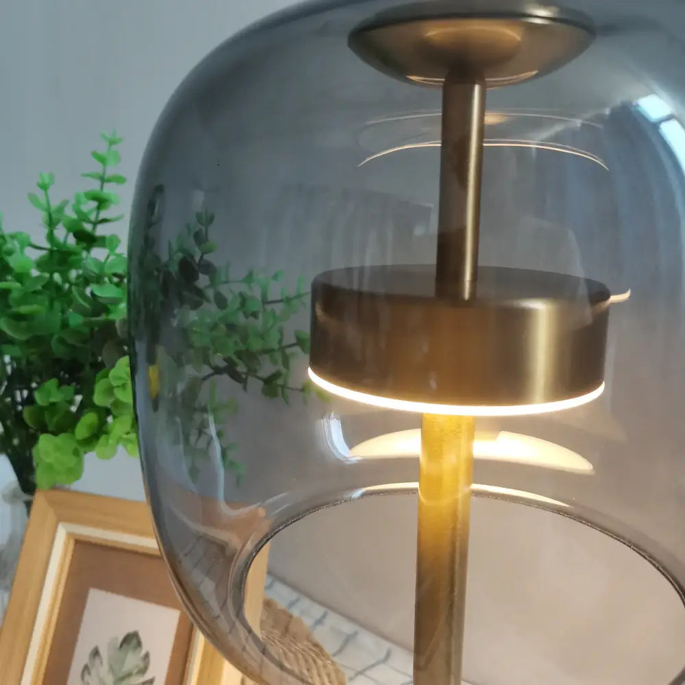 Modern gold and gray glass table lamp with translucent dome and illuminated ring for bedroom use