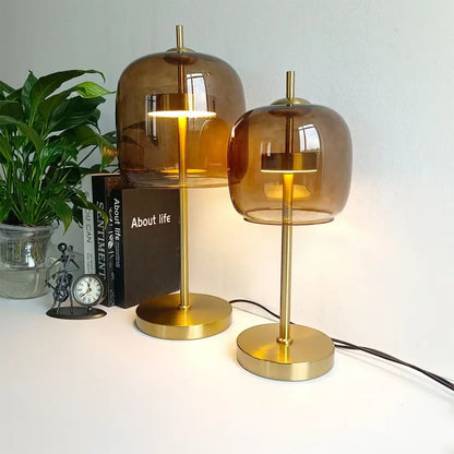 Two amber glass table lamps with brass bases featuring modern design as part of a bedroom glass table lamp set