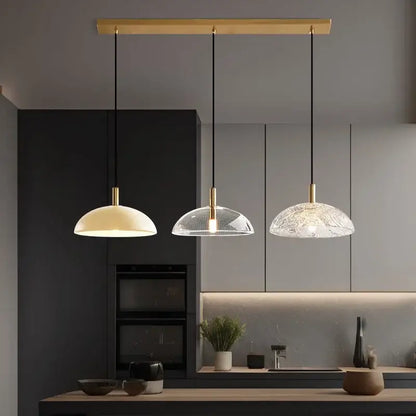 Three modern pendant lights with gold-finished fixtures and glass pendant shades for kitchen dining room lighting