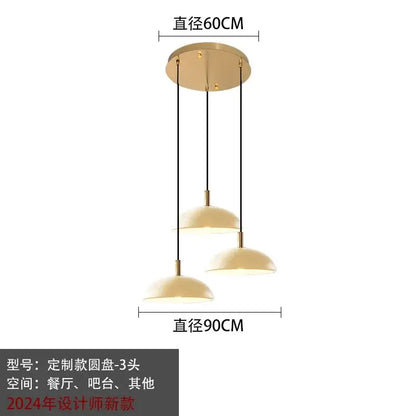 Modern gold pendant light with three cream dome glass pendant shades suspended by black cords for kitchen dining room