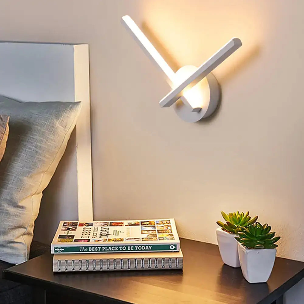 Modern gold angular wall lamp with sleek white arms emitting warm white light for bedroom use