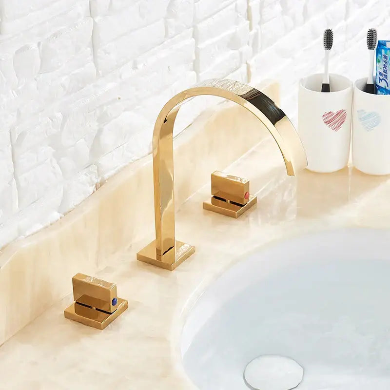Modern gold arched dual handle basin faucet set with sleek curved spout and square base plates for bathroom use